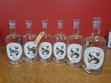 six bouteilles de gin posées sur une table en bois, avec une étiquette dessus