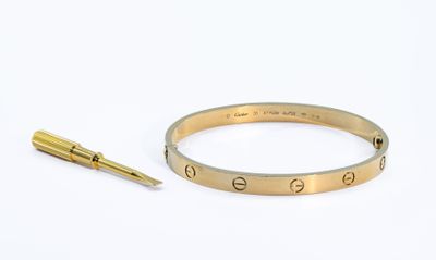 bracelet en or orné de la lettre « e » et d'un stylo sur un fond blanc