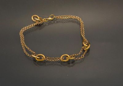 a close up of a gold chain bracelet on a black surface