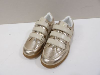 gold and white sneakers with velcro straps on a white surface