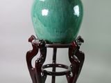 a green vase sitting on a stand on a white background