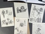 sketches of various characters are displayed on a table in front of an open book