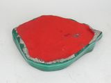 a red and green piece of pottery on a white surface