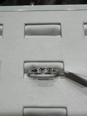 une bague en diamant dans une boîte blanche, accompagnée d'une paire de pinces