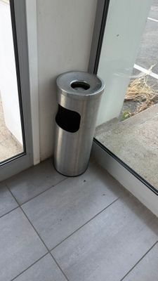 une poubelle devant une porte vitrée