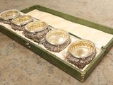 quatre bols en argent dans une boîte verte posée sur une table