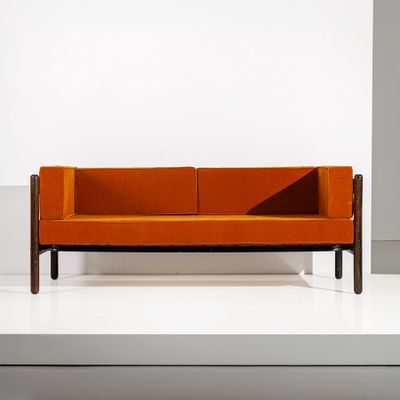 an orange couch sitting on top of a white platform next to a wall