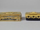 pair of gold and blue glass boxes on a white surface
