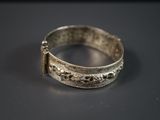 une vieille bague en argent posée sur une table, sur fond noir