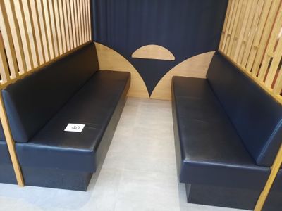 deux canapés en cuir noir dans une pièce séparée par une cloison en bois
