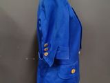 a blue jacket on a mannequin stand against a gray wall