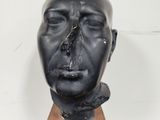 a black sculpture of a man ' s head on a wooden block