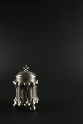 a small silver container with a lid on a black surface