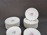 six assiettes blanches ornées de roses roses sont empilées les unes sur les autres