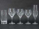 four wine glasses and a vase are lined up against a black background