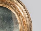 a round mirror with a gold frame on a wall