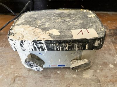 a dirty toaster sitting on the floor with a sticker on it