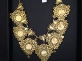 Un collier en or est exposé dans une vitrine noire