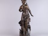 an antique bronze statue of a woman with a bird on her shoulder
