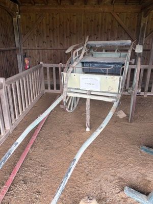 une image représentant un cheval dans une grange avec une clôture