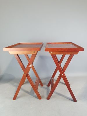 deux tables pliantes en bois, posées contre un mur et surmontées de plateaux