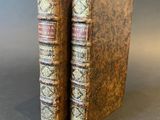 two old books sitting on top of each other on a table