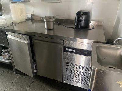 plan de travail en acier inoxydable dans une cuisine professionnelle, équipé d'un évier et d'un lave-vaisselle
