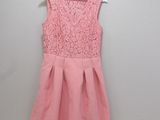 a pink dress hanging on a hanger against a wall