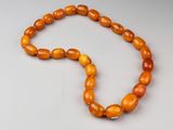 un collier de perles orange posé sur une surface blanche