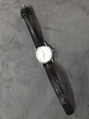 un gros plan d'une montre posée sur une table, avec un bracelet noir