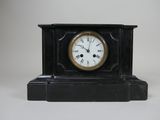 une petite horloge noire avec des chiffres romains