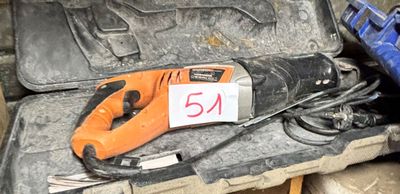 une perceuse électrique orange et noire posée sur une mallette à outils