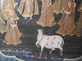 a painting on the wall of a building with a cow in front of it