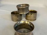 four silver cups sitting on top of a white cloth covered table