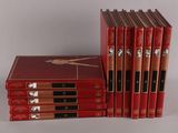 six livres rouges sont empilés les uns sur les autres sur une surface blanche