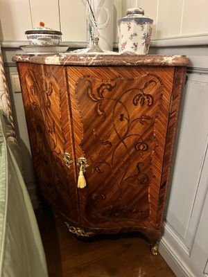 a wooden cabinet with a marble top next to a bed