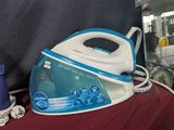 un fer à repasser à vapeur bleu et blanc posé sur un tissu rouge