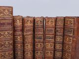 several old books are lined up in a row on a table