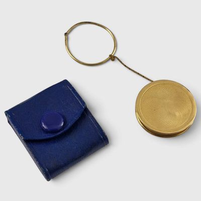 gold plated coin and blue leather case on a white surface