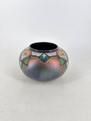 un vase coloré posé sur une table, sur fond blanc