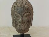 statue of a head on a black stand on a marble surface