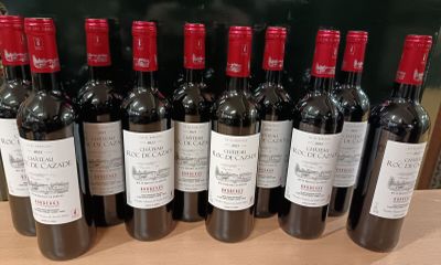 des bouteilles de vin rouge alignées sur une table devant un tableau noir