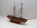 une maquette en bois d'un bateau posée sur une surface blanche