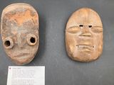 two wooden masks are on display on a black surface