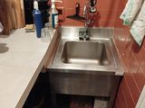 a sink in the corner of a kitchen with a towel hanging on the wall
