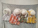 three hats hanging on a wall with clothes on it