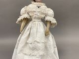 une poupée ancienne en porcelaine représentant une femme en robe blanche