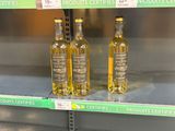 three bottles of olive oil on the shelves of a grocery store