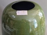 a green vase with a tag on it sitting on a table