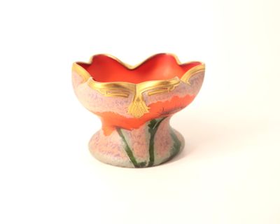 un petit vase posé sur une surface blanche